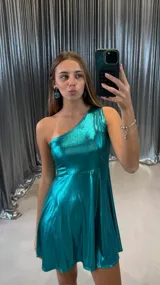 Vestido corto metalizado color turquesa, con escote asimétrico de un solo hombro y falda acampanada.