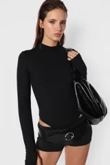 Body blanco de algodón con lycra, de manga larga con detalle de mitón en los puños y cuello media polera.