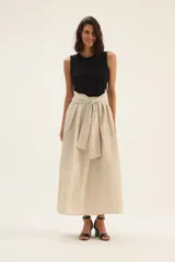 Falda larga color beige, de tafeta con moño en la cintura.