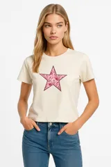 Remera color crema de corte recto y mangas cortas, con estampa de una estrella rosa con diseño floral.