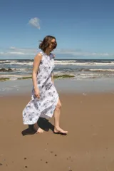 Vestido midi sin mangas con estampado floral azul sobre fondo blanco, tajos laterales y cierre con botón en la espalda.