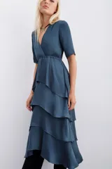 Vestido azul petróleo con escote en V, largo midi, mangas cortas, elástico en la cintura y falda con volados en capas.