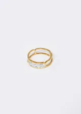 Anillo hipoalergénico de acero quirúrgico con diseño de contorno y detalle de strass.