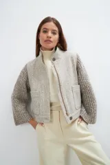 Campera con cuello alto y mangas en tejido de punto, con cierre frontal oculto y bolsillos de doble abertura, hecha de lana fina sin teñir.