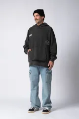 Buzo canguro negro de frisa rústica con corte oversize y capucha. Presenta un pequeño logo blanco en el pecho y un bolsillo tipo canguro.