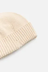 Gorro de lana tejido en punto morado oscuro, con vuelta y detalles rotos.