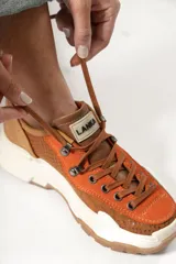 Zapatillas deportivas de color óxido con texturas combinadas y suela clásica.