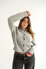 Cárdigan gris de tejido con relieve, cuello camisero, botones al frente y detalles de color rojo en cuello y puños.