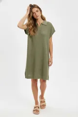 Vestido color verde oliva de tejido calado, con cuello tipo camisa, manga corta, corte recto y largo a la rodilla.