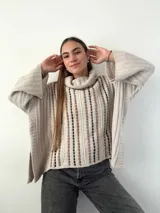 Sweater color crema de mohair con cuello alto y mangas anchas. Tejido con calados verticales y bordado a mano con lana merino.