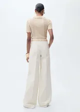 Pantalón de jean color crudo, de corte wide leg con tiro alto. Presenta trabillas, cierre frontal con cremallera y botón, dos bolsillos laterales y dos bolsillos de parche en la parte posterior.