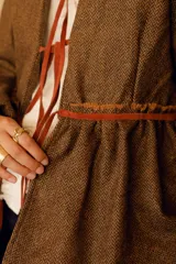 Chaqueta marrón de lana con forro de algodón y tiras de cuero. Diseño con cuello en V y corte a la cintura.