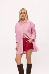 Camisa oversize a rayas verticales color amarillo y blanco, con cuello camisero, manga larga y cierre frontal con botones.