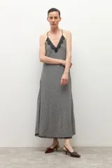 Vestido largo de tirantes finos, con escote en V decorado con encaje negro. El tejido presenta un estampado de cuadros vichy en blanco y negro.
