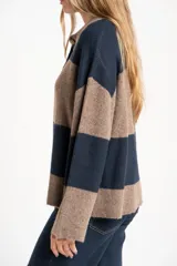 Sweater de tejido de punto grueso, color marrón y azul marino, con diseño de rayas horizontales anchas. Presenta cuello polo y abertura frontal con dos botones nacarados.