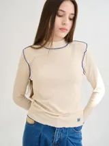 Polera negra de tela rib con cuello alto y mangas largas. Presenta pespuntes rojos en cuello, hombros y puños.