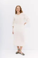 Vestido midi tipo túnica color blanco, de lino y algodón. Tiene calce recto, escote redondo con botones y bordados en hilo en el frente, sisas y ruedo.