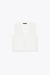 Top blanco de algodón con bordados florales, escote en pico, sin mangas y cierre frontal con lazos.