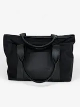 Bolso tote negro de lona con apliques de cuero y doble asa de mano.