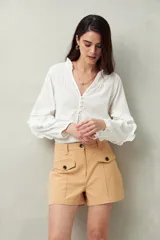 Short blanco de tiro alto con bolsillos delanteros con solapa y botones a la vista.