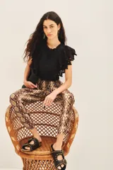 Pantalón babucha con estampado de piel de serpiente, ajuste en los tobillos, elástico en la cintura y cordón para ajustar. Cuenta con terminaciones metálicas, bolsillos diagonales en el frente y falsos bolsillos ojal en la espalda.