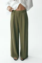 Pantalón verde militar de tiro medio con bolsillos delanteros y falsos bolsillos traseros. Detalle de pinzas en el delantero. Cierre frontal con cremallera y botón. Corte ancho.