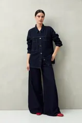 Sobrecamisa oversize de jean azul con cuello camisero, cierre frontal con botones, mangas largas y bolsillos de parche en el pecho.