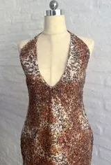 Vestido corto ajustado con escote profundo en V y cuello halter, cubierto completamente de lentejuelas con patrón moteado en tonos marrones, naranjas y blancos.