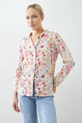 Camisa de manga larga con cuello clásico y estampado floral multicolor sobre fondo blanco.