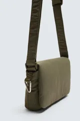 Bandolera negra de tela técnica con correa ajustable. Tiene un compartimento principal con cierre de solapa e imán, y un bolsillo plano interior.