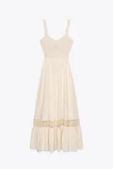 Vestido midi color crudo, con breteles anchos y escote recto. La parte superior es de tejido de punto calado y la falda es lisa con volado y detalle de puntilla en el ruedo. Tiene abertura en la espalda y cintura elastizada.