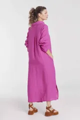 Vestido camisero largo color fucsia, de lino, con cuello camisero, mangas largas, cierre frontal con botones, bolsillos laterales y aberturas laterales en el ruedo.