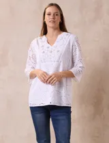 Blusa blanca de broderie con cuello a la base y escote en V. Apliques de brillos y piedras nacar en la parte delantera.
