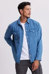Camisa de jean celeste de manga larga con cuello clásico, cierre con botones a presión y dos bolsillos con solapa abotonada en el pecho.