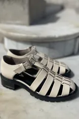 Sandalias de cuero color cobre con diseño de tiras entrecruzadas, hebilla lateral y suela track color negro.