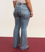 Pantalón de jean azul claro, modelo flare, con cintura elástica, trabillas para cinturón, bolsillos delanteros y traseros, y botón en forma de flor.