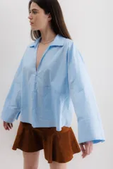 Camisa blanca de algodón con cuello clásico, mangas largas con puños abotonados y bolsillo de parche en el frente.