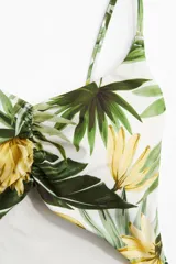 Traje de baño entero con estampado de hojas y flores amarillas, escote en V, breteles finos ajustables, copas con relleno extraíble, detalle fruncido en el busto y abertura cut-out en la cintura.