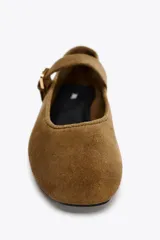 Zapato plano tipo bailarina en serraje color marrón. Escote redondo y cierre mediante hebilla en el empeine.