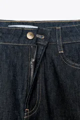 Pantalón de jean azul oscuro, de tiro alto y corte wide leg. Tiene cinco bolsillos, cierre frontal con cremallera y botón.