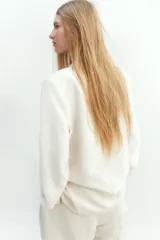 Blazer blanco de doble botonadura con solapas de muesca, hombreras y bolsillos delanteros ribeteados con solapa.