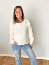 Sweater color crudo de tejido liviano con detalle calado en hombros y mangas levemente abullonadas.