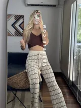 Pantalón de hilo color marrón con rayas horizontales blancas, corte holgado y cintura con cordón ajustable.