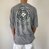 Remera gris con efecto gastado y estampado en la espalda con diseño abstracto en tonos verdes y blancos.