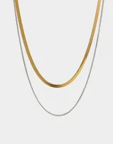 Set de dos collares cortos de acero quirúrgico, uno dorado de eslabones planos tipo espiga y otro plateado de eslabones finos.