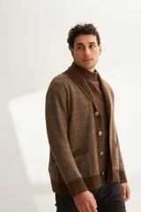 Cardigan tejido color marrón con cuello smoking, cierre con botones y bolsillos delanteros.