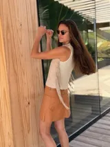 Top color beige de cuero con flecos en los laterales y caracoles buzios en el frente. Espalda tejida.