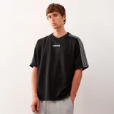 Camiseta negra de Adidas Originals con cuello redondo y mangas cortas. Presenta el logo de Adidas bordado en el pecho y las tres líneas características de la marca en color blanco sobre los hombros y mangas. Corte oversize.