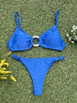 Bikini de dos piezas color azul vibrante. El corpiño es tipo top con un detalle de hebilla redonda dorada en el centro. La bombacha es colaless entera con frunces ajustables en los laterales.