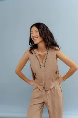 Chaleco color beige de lino con bordados en el cuello y en la parte inferior. Tiene cuello en V y cierre con botones.